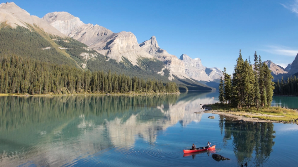 Canoers enjoying views of Jasper National Park from Maligne Lake in spring.