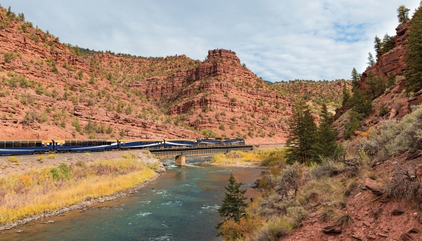 Rocky Mountaineer luxury train traveling through a rugged canyon landscape.