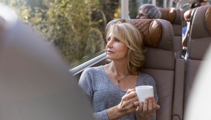 women gazes out window while holding coffee onboard rocky mountaineer in silverleaf service
