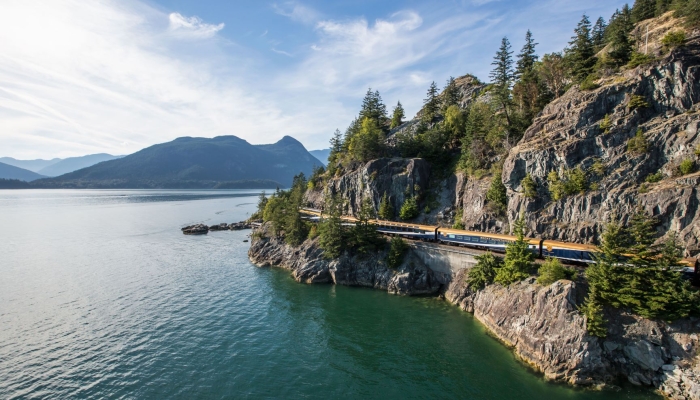 Rocky Mountaineer train travelling alongside the Sea-to-Sky highway and the Howe Sound