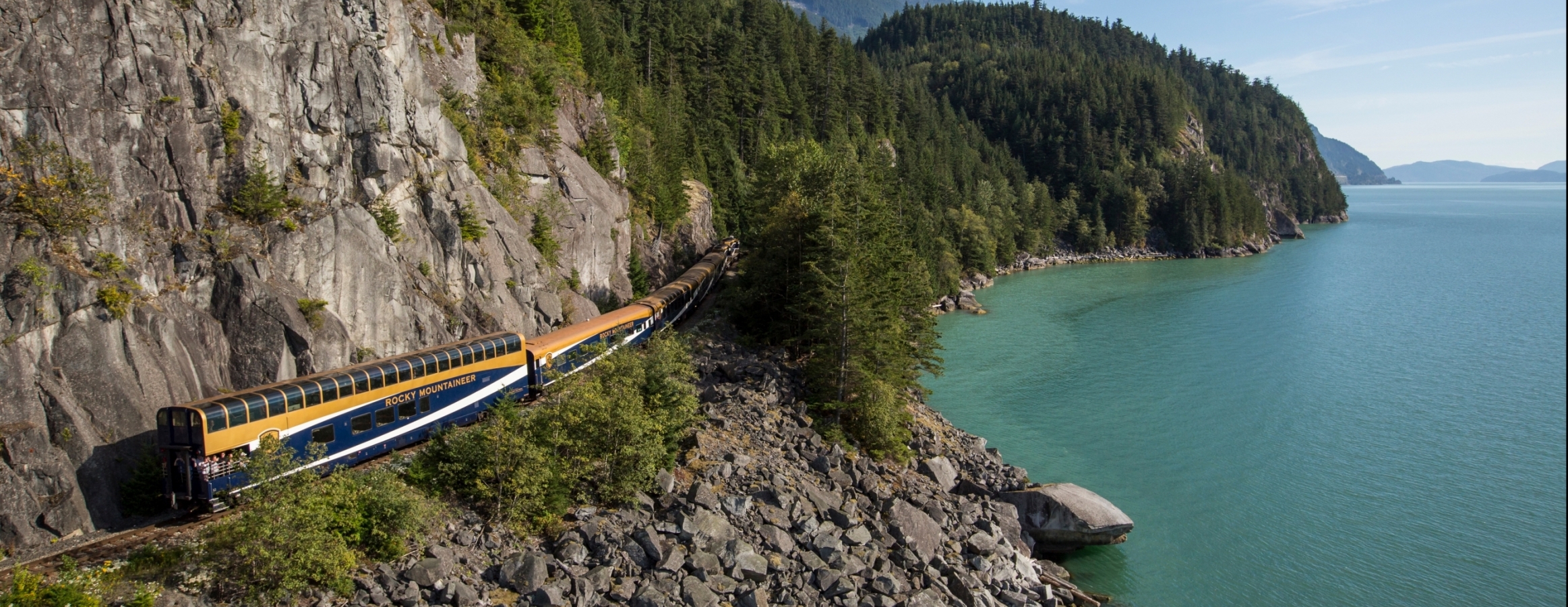 Rocky Mountaineer train travelling alongside the Sea-to-Sky highway and the Howe Sound